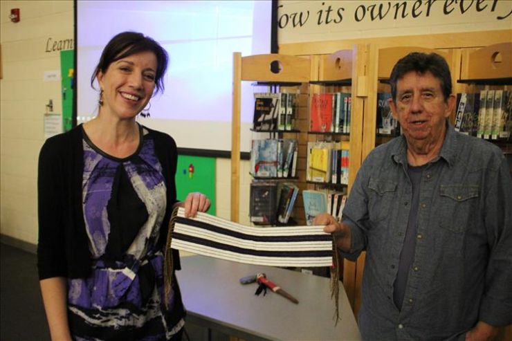 Two people hold a wampum belt