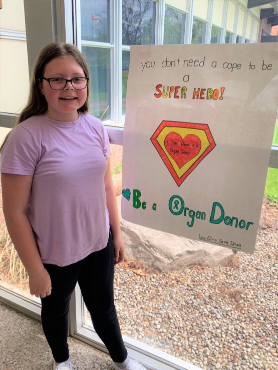 A student poses with a homemade poster promoting organ donation