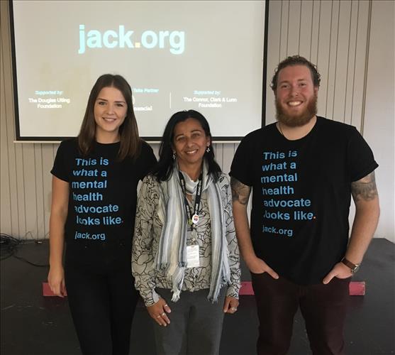 Three people stand in front of a mental health display 