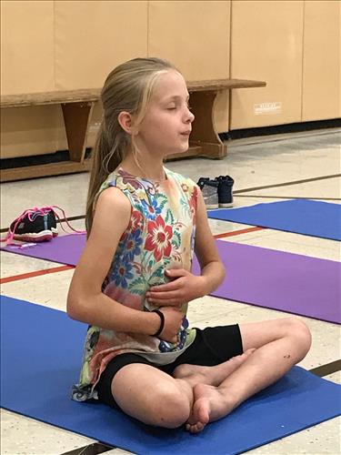 A young student sits on a yoga mat 