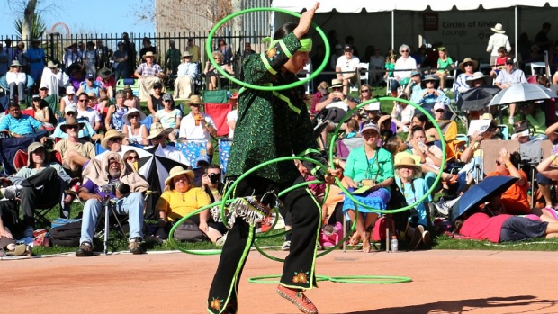 A male in regalia performs a hoop dance