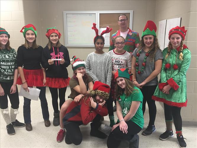 A group of students wearing holiday elf hats organizes canned goods
