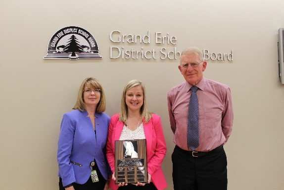 Director of Education and Chair of Board stand with woman holding plaque