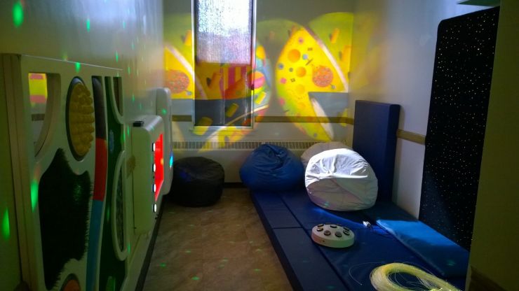 A multi-sensory room with soft lighting and furniture provides relaxing environment