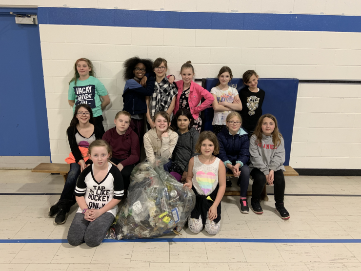 Students pose with a large bag of garbage they collected
