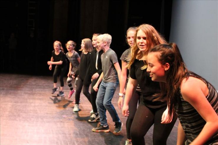 A group of students performs a scene on stage