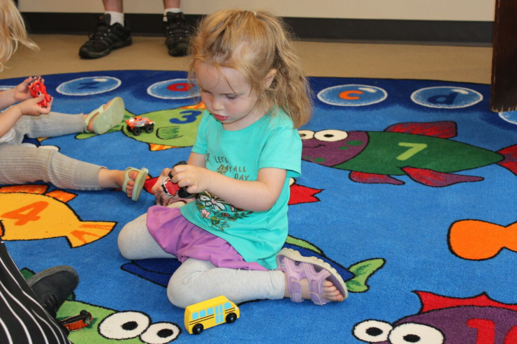 A child plays with toys on a colourful mat