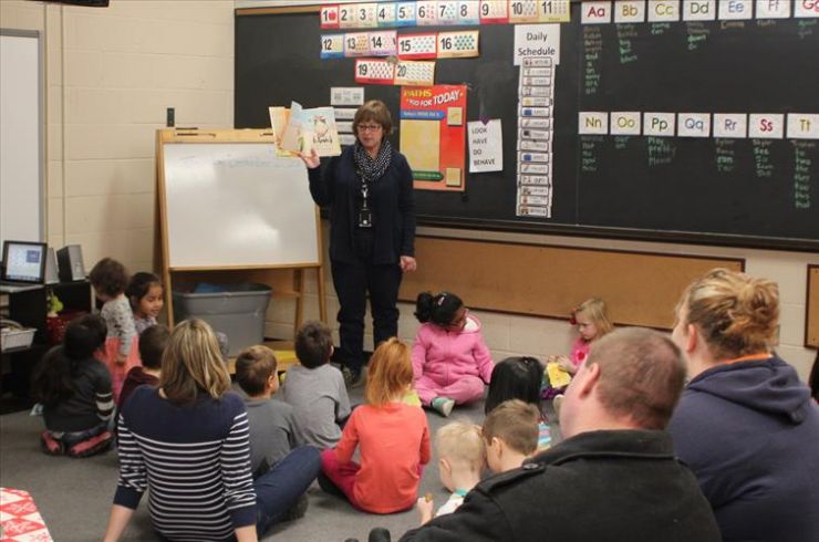 A Child and Youth Worker reads a story to a group of Grade 1 students