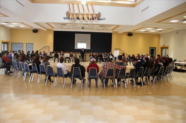 A group of students sits in a circle in a hall