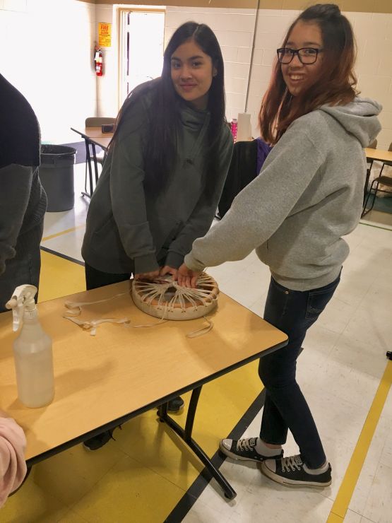 Two students work to construct a drum