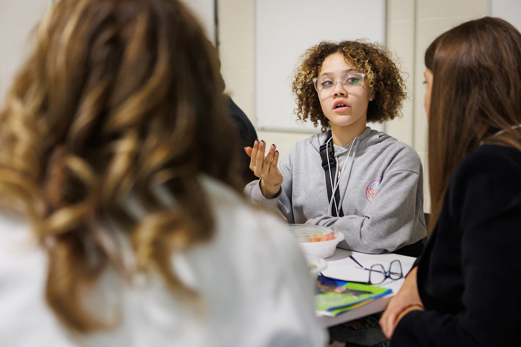 Young student sitting at group table engaged in discussion